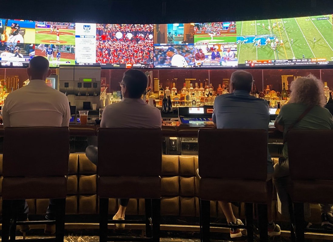 Group of people at a bar watching TV (Unsplash photo)